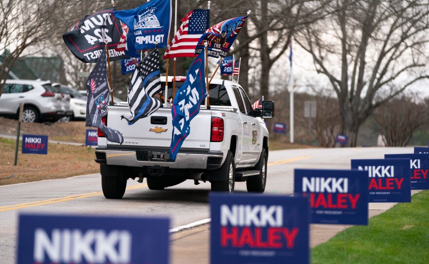 A supporter of former President Donald Trump drives past campaign signs for Republican presidential candidate Nikki Haley in Irmo, South Carolina. The state's Republican presidential primary is on Feb. 24.
