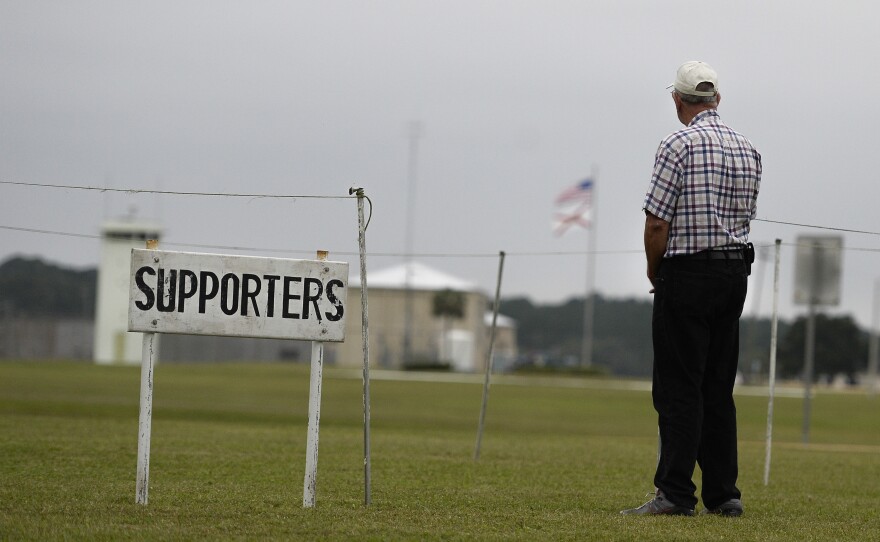 A lone supporter of the execution of William Happ stands across the highway from the Florida state correctional facility on Oct. 15. Happ was the first inmate to be put to death using the drug midazolam.