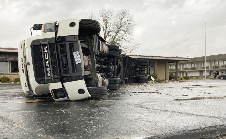 A large semi is flipped over and pushed against a building in Bowling Green, Ky., on Saturday.