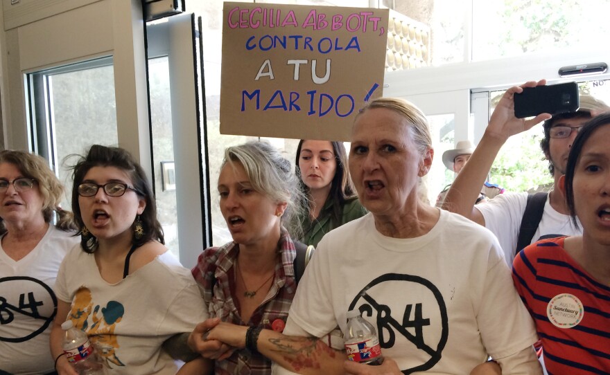 Protesters rally during a sit-in at the Texas Department of Insurance building in Austin last week. They oppose the bill that Gov. Greg Abbott signed into law Sunday. It compels police to enforce federal immigration laws.