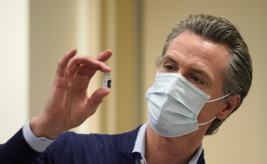 California Gov. Gavin Newsom holds up a vial of the Pfizer-BioNTech COVID-19 vaccine at a Los Angeles medical facility. Coronavirus cases continue to soar in the state as hospitals struggle to keep up with the surge.
