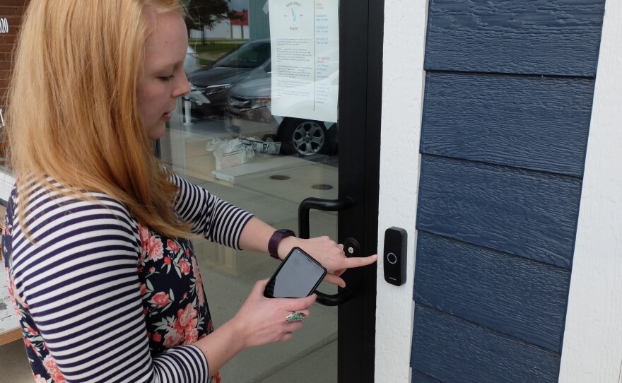 Caileen Ostenson demonstrates the phone app that allows members to open the market any time they want to shop.
