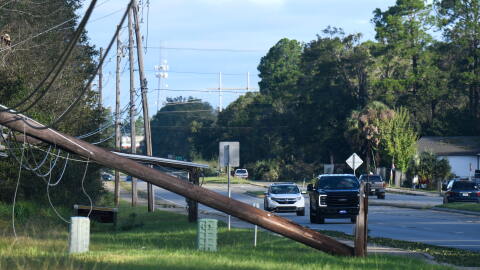 Vehicles pass a utility pole brought down by the effects of Isaias on Saturday, Oct. 10, 2026, in East Milton, Fla.