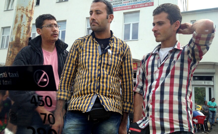 Monzer Omar (center) and his friend Hatem Alhees (right) camped out for days outside a strip mall and hotel in a rundown part of Budapest, after Hungarian authorities kicked them out of Keleti station. The hotel would not admit them.