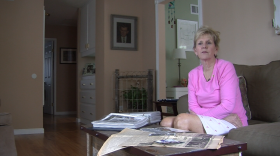 Patty Lee stares out her living room window after displaying photos and articles of her father, an Army master sergeant killed in Vietnam in 1967. A portrait of her dad, Delbert C. Totty, and part of a fence she helped him create are shown in the corner behind her. 