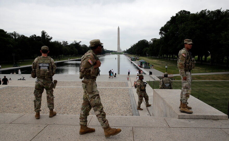 Members of the National Guard patrol as National Park Service workers clean algae from the Lincoln Memorial Reflecting Pool in Washington, D.C.