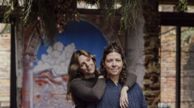 Newlyweds Emma Brennan, left, and Lauren Wright stand in the first floor of their home, in front of a mural they had painted for their wedding, in Baltimore, Md. on Tuesday, Jan. 6, 2026.
