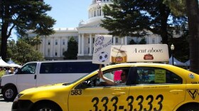 In this 2014 photo, a taxi driver urges the California Legislature to require drivers for ride-hailing companies like Lyft and Uber to maintain commercial auto insurance, as taxi drivers do. Lawmakers passed a compromise bill in August.