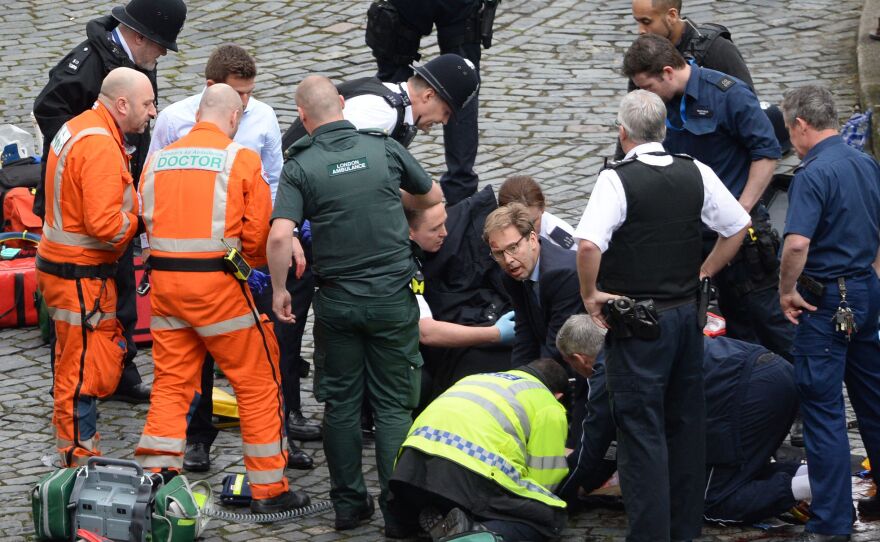 Conservative MP Tobias Ellwood helps emergency services attend to a police officer outside the Palace of Westminster, London, after a policeman was stabbed and his apparent attacker shot by officers in a major security incident at the Houses of Parliament.