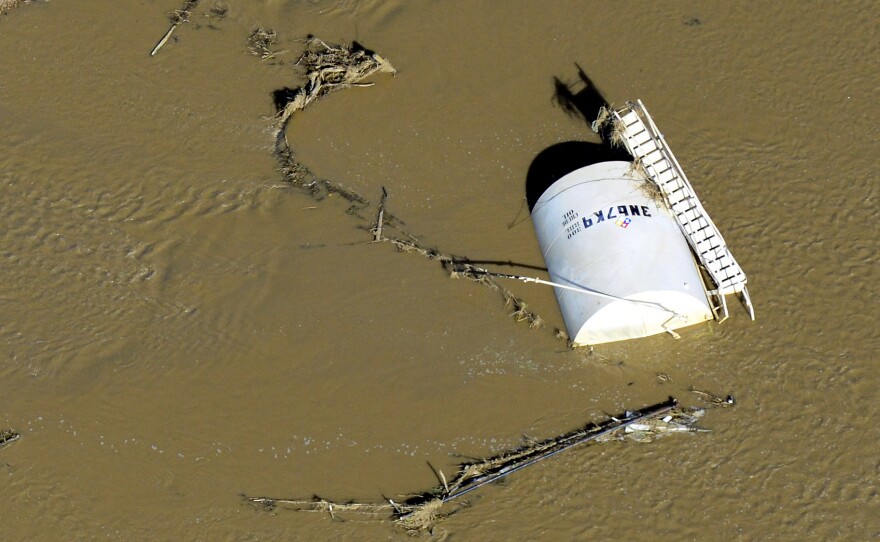 A crude oil storage tank lies on its side in floodwaters along the South Platte River, in Weld County, Colo., on Sept. 17. Hundreds of natural gas and oil wells along with pipelines are shut down by flooding, as state and federal inspectors gauge the damage and look for potential contamination from inundated oil fields.