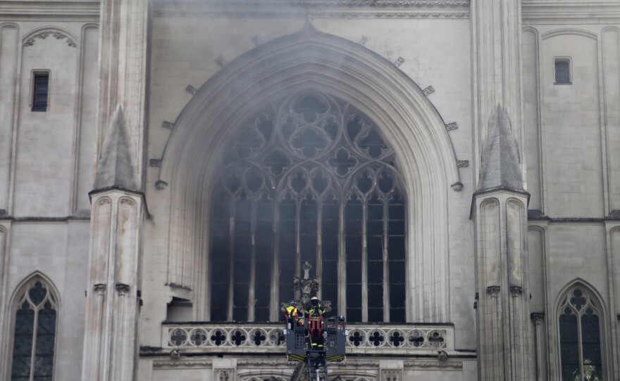 Firefighters work to extinguish the blaze at the Cathedral of St. Peter and St. Paul in Nantes on Saturday. The fire shattered stained-glass windows and sent black smoke billowing from between its two towers.