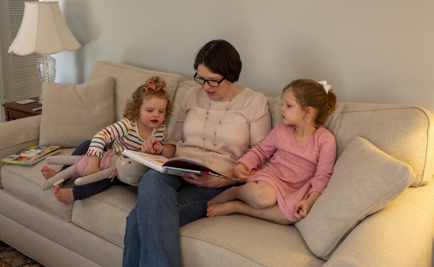 Terry reads to her daughters as they snuggle with her on the couch.