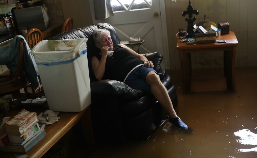 Elsie Lazarus is overcome with emotion Thursday as she sits in her flooded living room while retrieving what she can from her home in St. Amant, La.