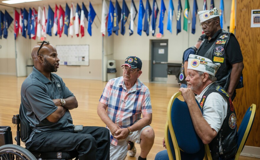 Sherman Gillums Jr., (left) chief strategy officer of AMVETS, speaks with veterans at the Heal American Veterans Town Hall in Smyrna, Tenn. AMVETS hosted the meeting to hear from service members, veterans and family members.