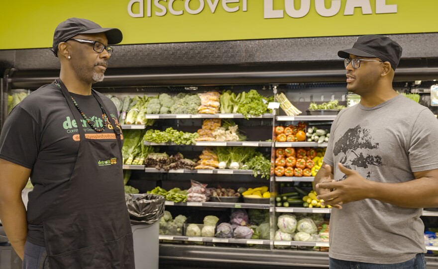 Biologist Shane Campbell-Staton (left) talks with a worker at a grocery store.