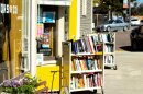 Libélula Books pictured from the sidewalk, with a yellow door and two carts of books outside.