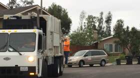 San Diego Mayor Kevin Faulconer rides on the back off a trash truck, Sept. 1, 2015. 