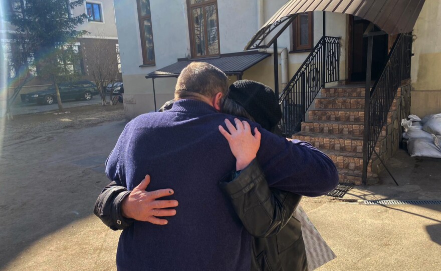 Bohdan Ivanchuk, principal of the music school, hugs Maj. Tarabalka's parents, Natalia and Ivan Tarabalka, as they mourn the death of their son killed in combat over Ukraine.