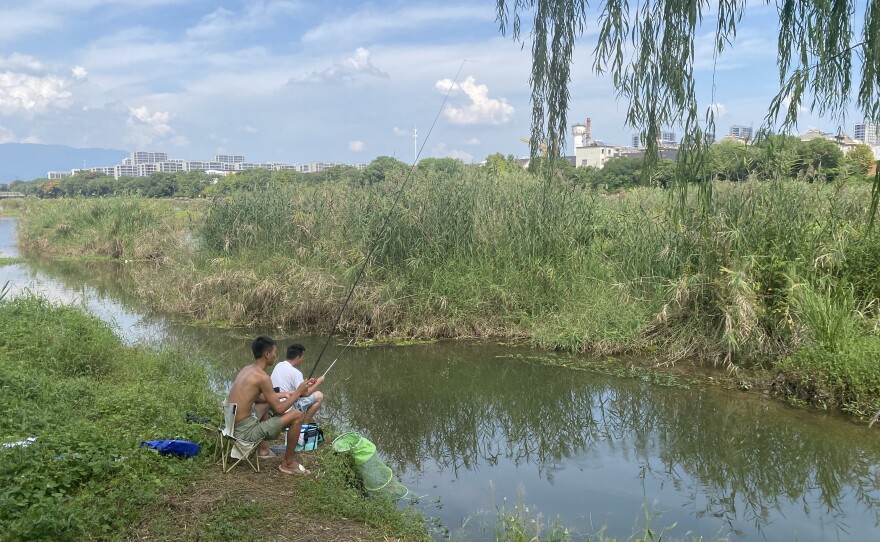 Li Tao and his buddy dabble lines in a slow-moving river channel in Jinhua, China, occasionally pulling out a tiny fish.