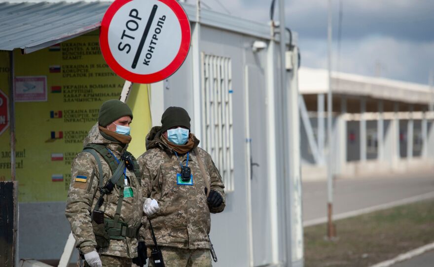 Ukrainian border guards wear protective face masks at a checkpoint with the territories controlled by Russia-backed separatists in the Donetsk region.