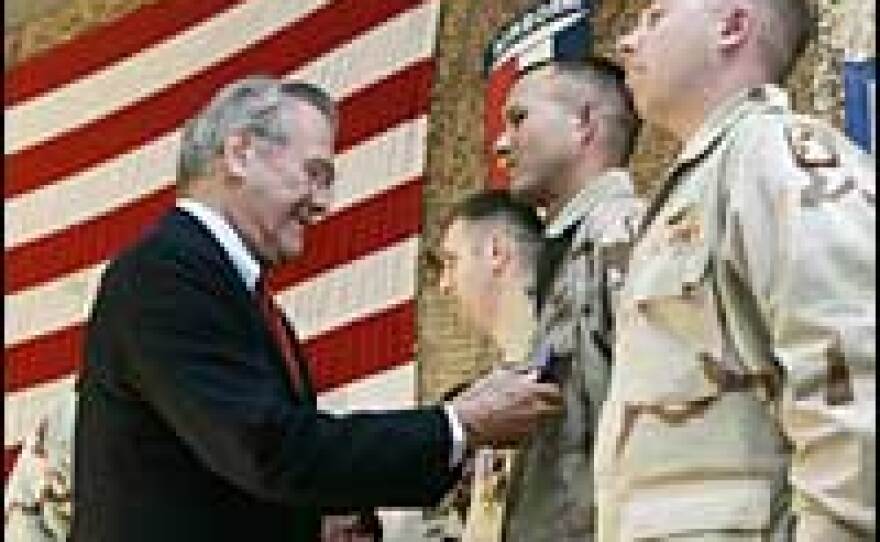 Secretary of Defense Donald Rumsfeld presents medals to Sgt. Ryan Pummill (R), Sgt. John Irick and Chief Warrant Officer 2 Steven Burr at Bagram Air Field near Kabul, Afghanistan, Dec. 22.