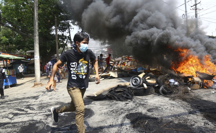 Anti-coup protesters are shown running around their makeshift barricade on March 28, 2021, as they make a defense line during a demonstration in Yangon, Myanmar, Sunday, March 28, 2021.