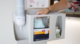 A woman at Palomar Health takes a mask from one of the many stands provided by the center.