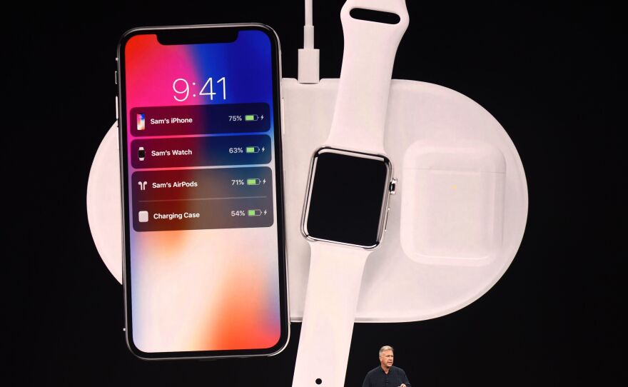 Apple executive Philip Schiller presents a wireless charging system, displayed with the new iPhone X and Apple Watch alongside cordless headphones called AirPods.