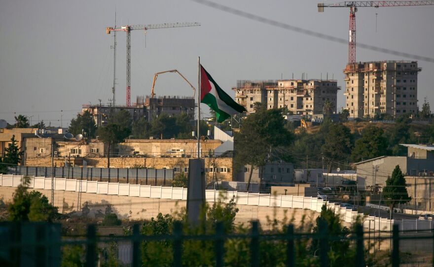 A Palestinian flag waves at the northern entrance to the city of Ramallah in the occupied West Bank as construction works take place in the Israeli settlement of Beit El in the background. Israel intends to annex West Bank settlements and the Jordan Valley, as proposed by President Trump, with initial steps slated to begin July 1.