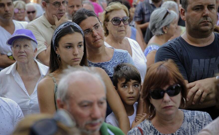 People observe a minute of silence in memory of the terror attack victims in Cambrils, Spain, Friday, Aug. 18, 2017.