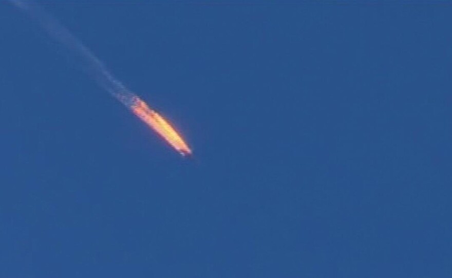 A frame grab from video on Turkey's Haberturk TV shows a Russian warplane on fire before crashing on a hill as seen from the Turkish side of its border with Syria on Tuesday. Turkey says it shot down the Russian plane because it was in its air space. But Russia says the plane was over Syria and was on a mission to bomb the Islamic State.