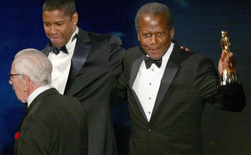 Sidney Poitier walks off the stage with presenter Denzel Washington after receiving an honorary Oscar during the 74th Academy Awards at the Kodak Theater in Hollywood, 24 March 2002.