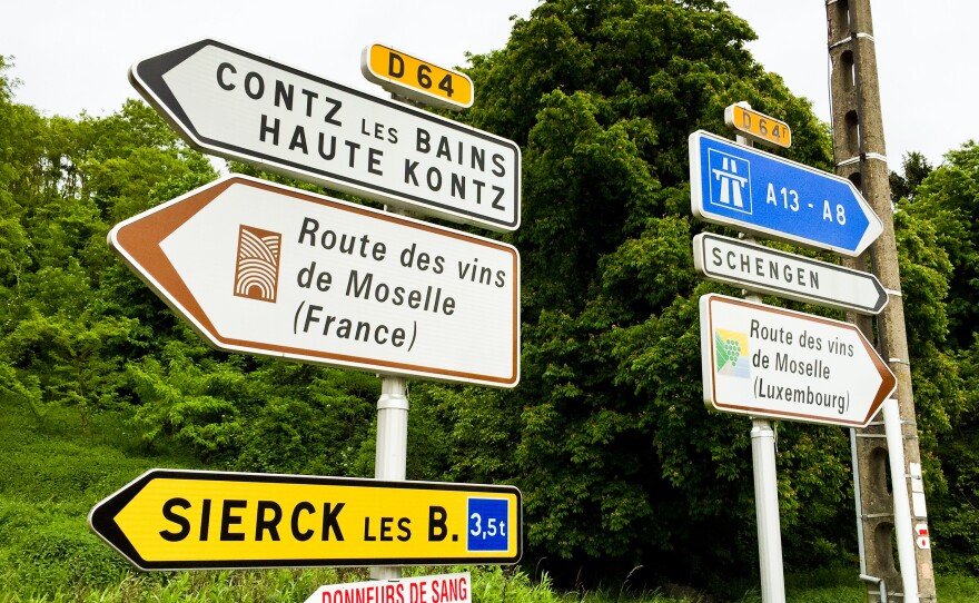Signs along the Moselle River, south of Schengen, where a 1985 agreement eased border restrictions among EU nations, mark a point where commuters from France and Germany pour across every day to work in Luxembourg.