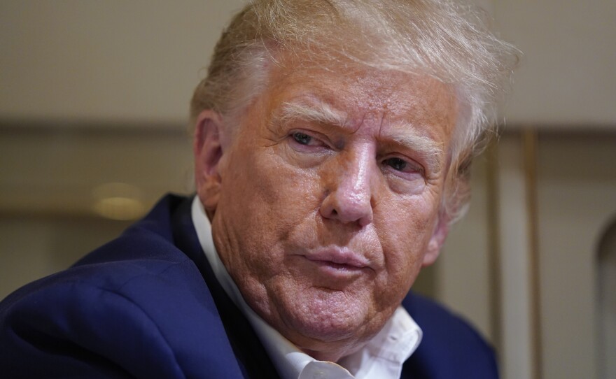 Former President Donald Trump listens as he speaks with reporters while in flight on his plane after a campaign rally at Waco Regional Airport, in Waco, Texas, Saturday, March 25, 2023, while en route to West Palm Beach, Fla.