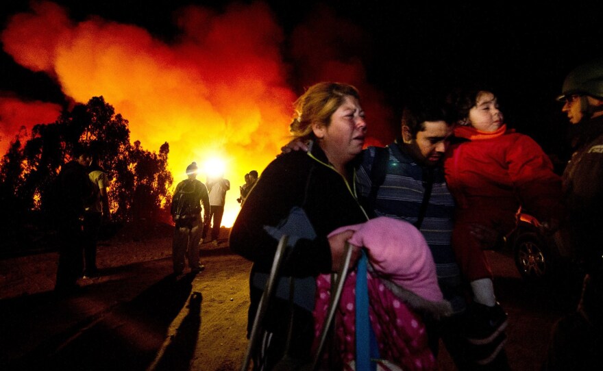 People flee after a rejuvenated fire threatened their neighborhood in Valparaiso, Chile, Sunday. More than 10,000 people have been evacuated because of the fire.