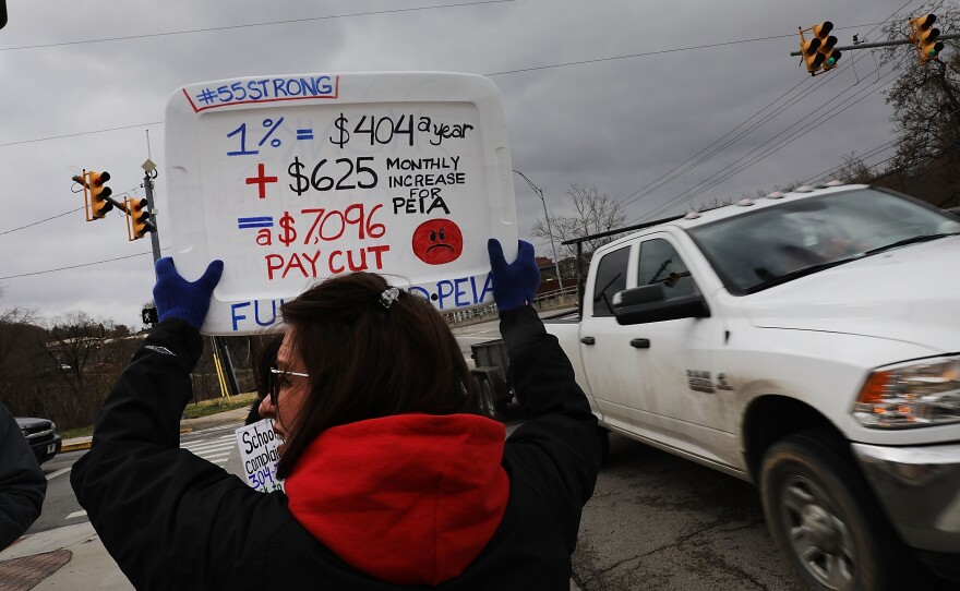 W. Va. teachers, students and supporters hold signs on a Morgantown, W. Va., street on Saturday. The strike is in its second weekend after the state Senate failed to pass the 5 percent raise teachers are demanding.