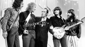 Creedence Clearwater Revival on stage with Ed Sullivan (Center). "Proud Mary" by Creedence Clearwater Revival is one of many classic rock hits featured in this special.
