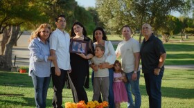From left, Julie Estrada, Matthew Estrada, Cheyenne Estrada, Brandie Curtis, Cash Curtis, Illiana Curtis, Jeff Curtis and Larry Estrada stand for a portrait behind Ciara Estrada's grave at the Murrieta Valley Cemetery District in Murrieta, California on Oct. 4, 2025. (Kori Suzuki / KPBS)