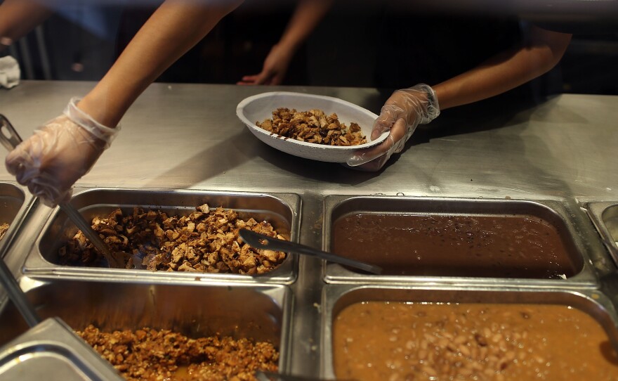 Chipotle restaurant workers fill orders for customers. The company is now sourcing some of its pork from a British supplier that uses antibiotics to treat pigs when ill. Gail Hansen, a veterinarian and longtime critics of the overuse of antibiotics on farms, welcome this shift in Chipotle's stance on the drugs.