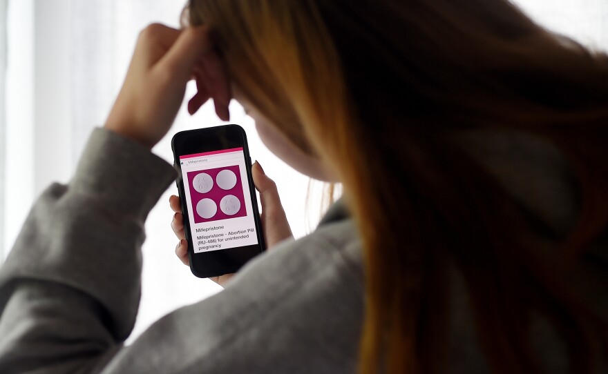 In this photo illustration, a person looks at an abortion pill (RU-486) for unintended pregnancy from Mifepristone displayed on a smartphone on May 8, 2020, in Arlington, Va. Under federal law, even in states where telemedicine abortion is legal, there are strict rules surrounding how the pill is dispensed.