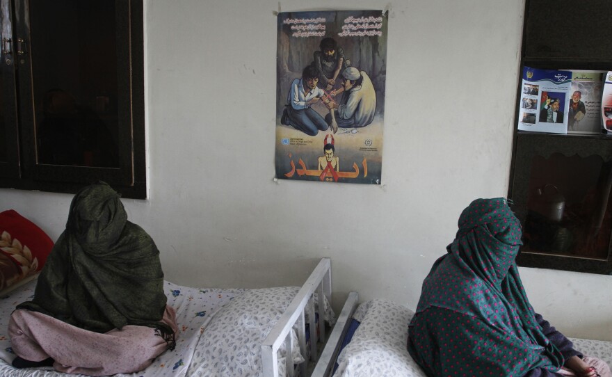 Two women sit, with their faces covered, at a drug treatment center in Kabul, Afghanistan.