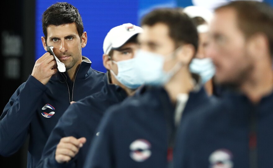 Novak Djokovic will play in the 2022 Australian Open, after getting an exemption from vaccine requirements. He's seen here removing his mask at the 2021 ATP Cup at Rod Laver Arena in Melbourne last February.