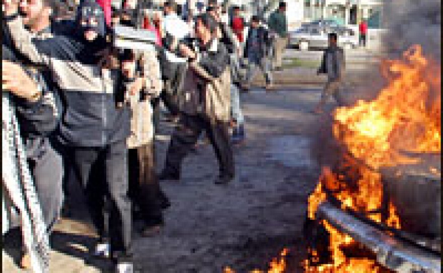 A masked gunman keep civilians away from a burning Iraqi National Guard vehicle following an attack in Mosul on Dec. 9.