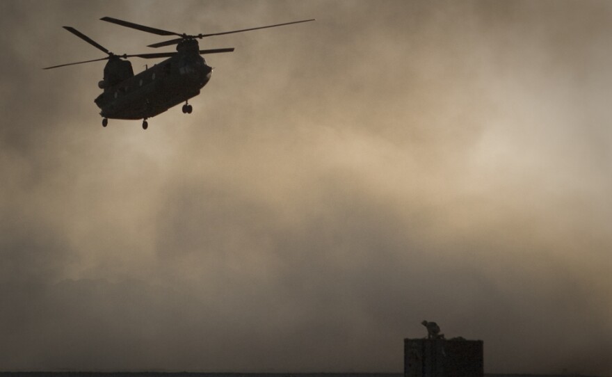A U.S. Marine tries to take cover as a Chinook helicopter arrives at Forward Operating Base Edi in the Helmand Province of southern Afghanistan, Thirty Americans were killed when a helicopter crashed in eastern Wardak province early Saturday.
