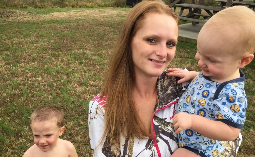 Brittany Crowe just completed an addiction treatment program that helped her regain custody of her children. Here she holds Allan, who was born with neonatal abstinence syndrome, as her son James stands behind them.