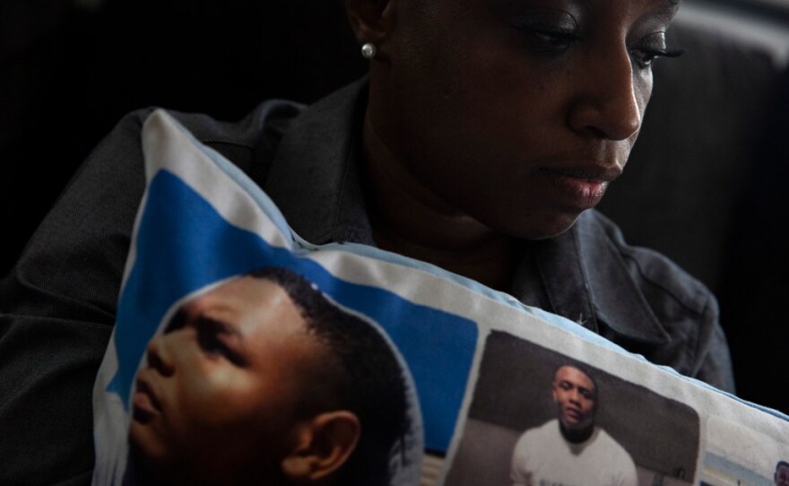 Jennifer Maraston holds a pillow covered in photos of her son Jaquan Wyatt, who was murdered the day after he turned 21 while traveling in California. It has been nearly two years since his homicide, but court proceedings have been delayed by challenges involving COVID-19 and the number of people charged in the case. 