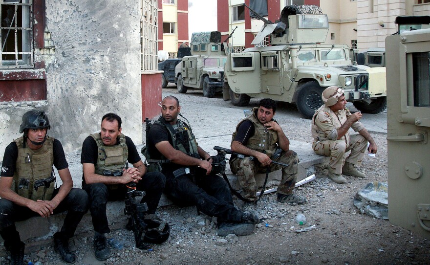 Iraqi security forces rest on a sidewalk following clashes with militants last month in Ramadi, the capital of Anbar Province. So far, the Iraqi forces have not been able to recapture cities and towns in western Iraq that the Islamic State seized earlier this year.