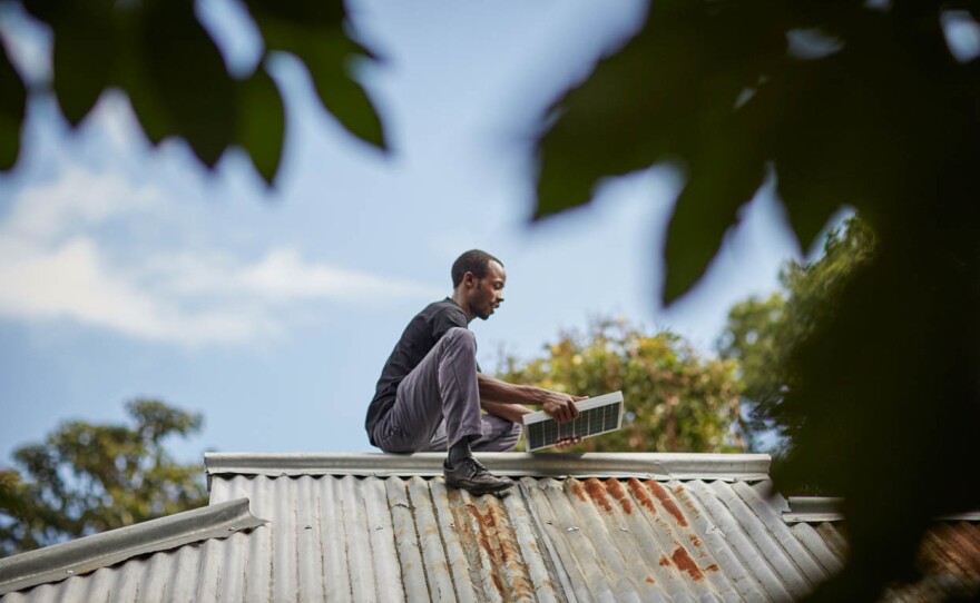 This undated photo shows a man holding a solar panel on a roof. Panels are part of Off-Grid's solar energy kit.