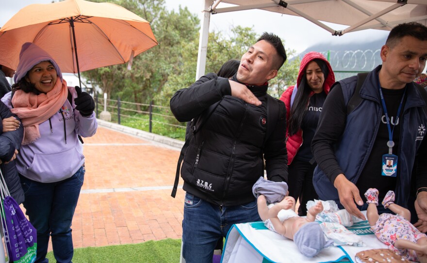 Nelson Alexander Yaguara pretends to wave away the stink of a soiled baby diaper at a pop-up workshop in Bogotá's San Cristóbal neighborhood.