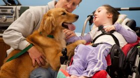Julia's dad, Tom, helps her bond with her assistance dog, Thelma, during the Canine Assistants training camp.
